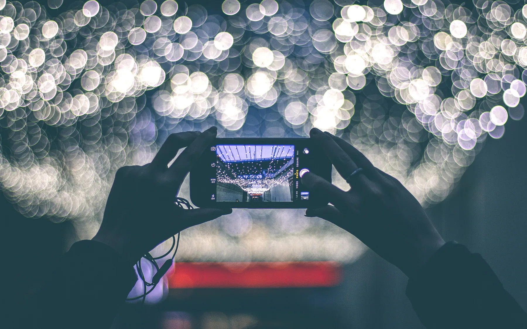 Two hands filming a lit stage on a phone