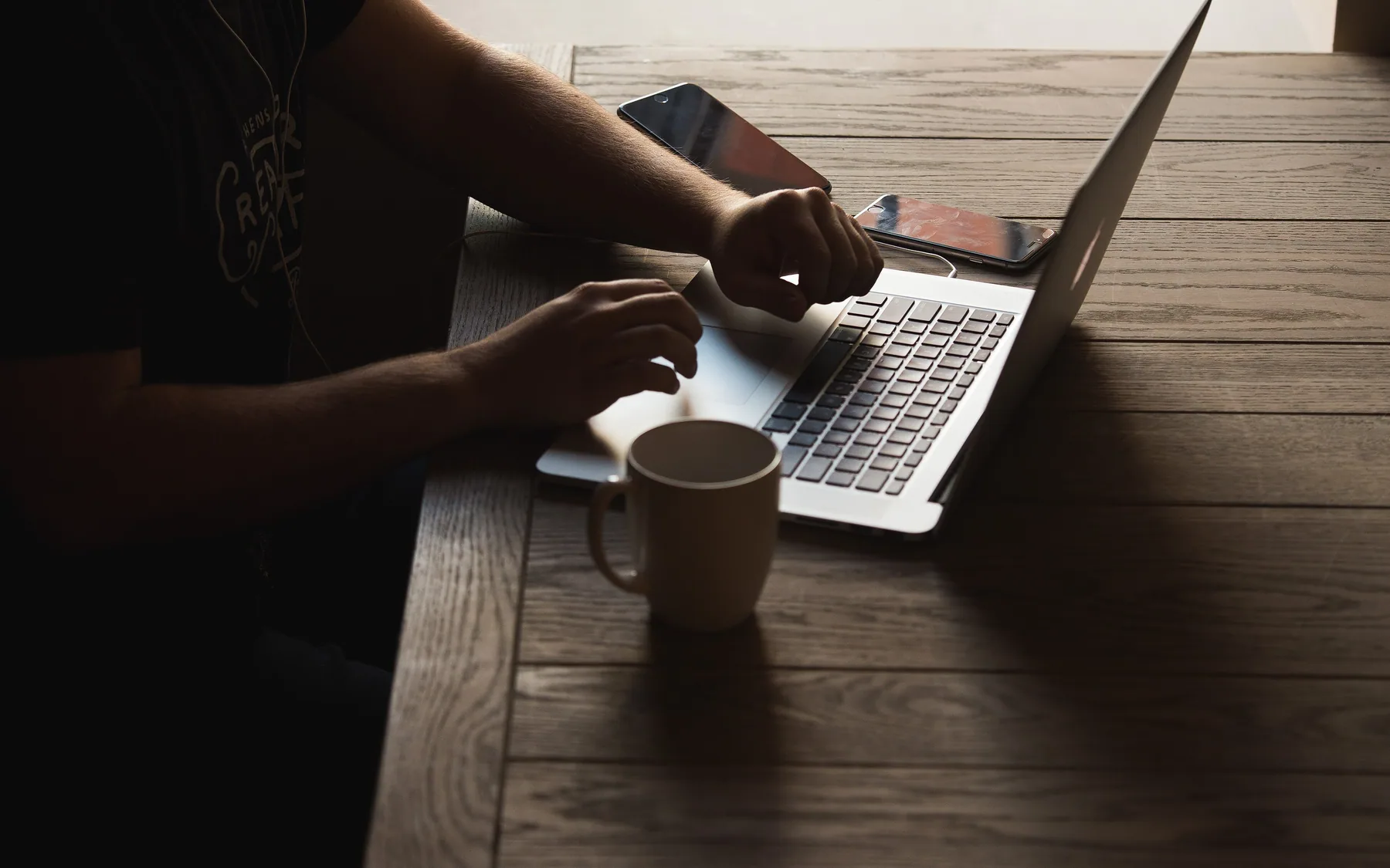 Two people working together over a laptop at a wooden table