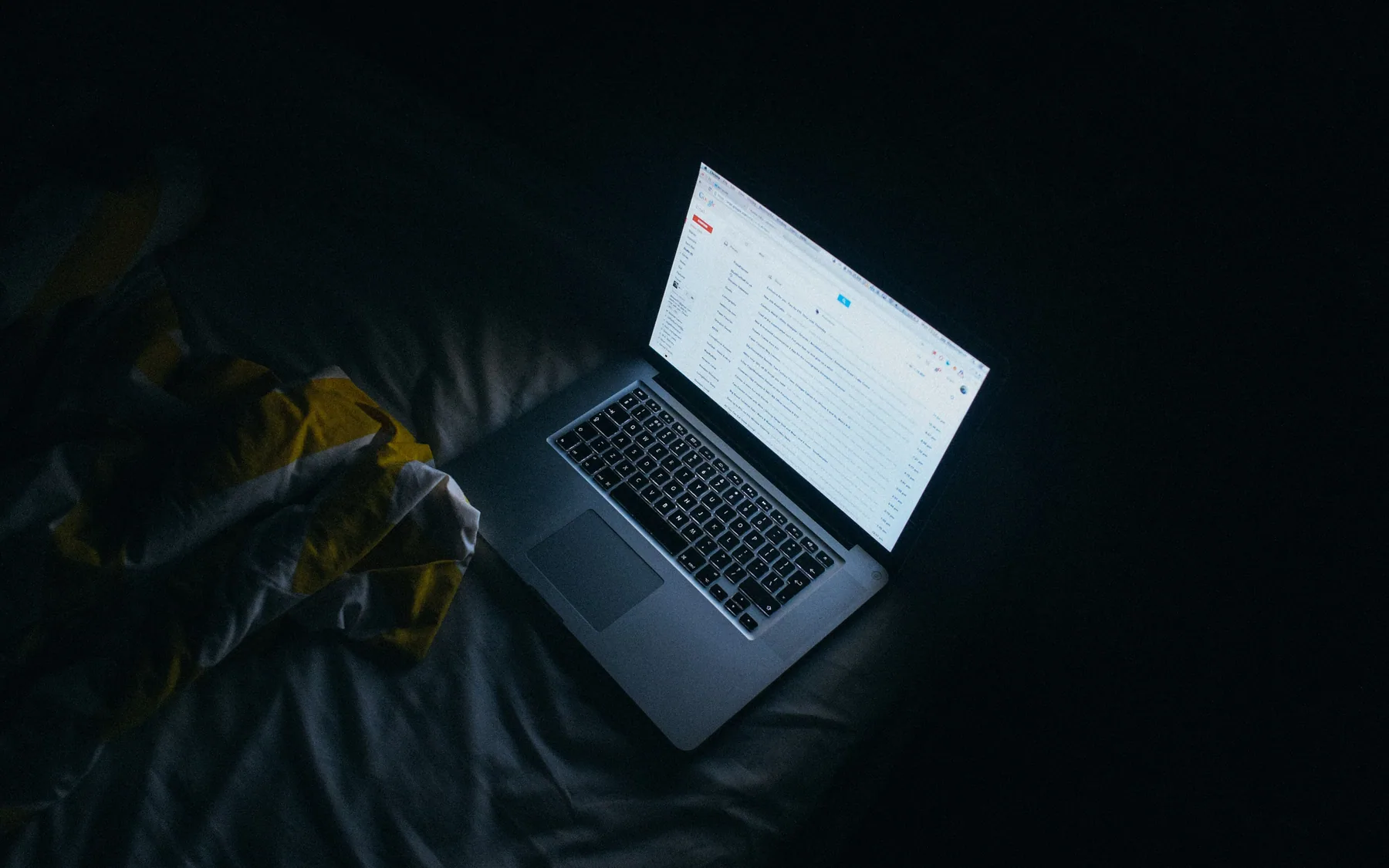 A laptop screen glowing in a dark room late at night